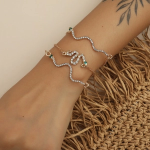 Detail of three-piece gold snake bracelet set with sparkling rhinestones on model's wrist