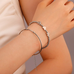 Silver bead bracelet with heart charms and slim adjustable bangle set on a model wrist
