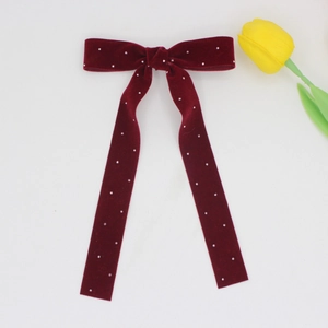 Elegant deep red velvet bow hair clip with faux pearl embellishments on white backdrop