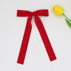 Detail of red velvet bow hair clip with pearls and long ribbons on white background