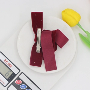 Burgundy velvet bow hair clip with white pearls on a scale showing 6g product weight