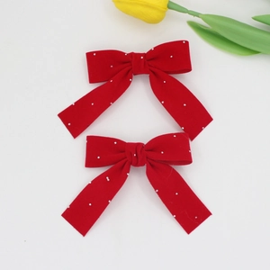 Detail of red velvet bow hair clips with sparkling glitter and soft fabric texture