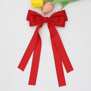 Détail d'une grande pince à cheveux nœud en satin rouge avec rubans et tulipes