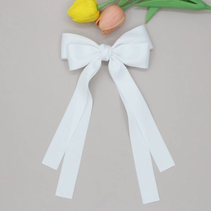 Vue détaillée du grand nœud papillon en satin blanc avec longs rubans pour les cheveux