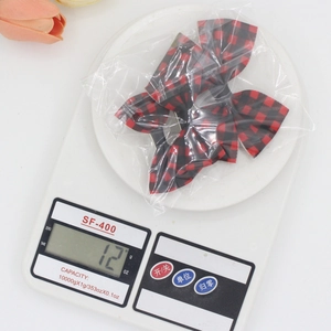 Detailed view of red and black plaid ribbon hair clips being weighed for shipping