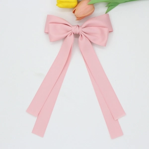 Détail d'une pince à cheveux nœud en satin rose mat avec de longs rubans sur blanc