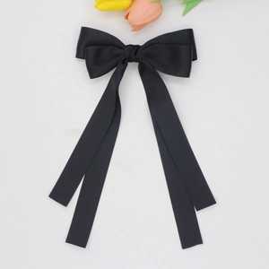 Détail d'une élégante pince à cheveux en satin noir avec un grand nœud et rubans
