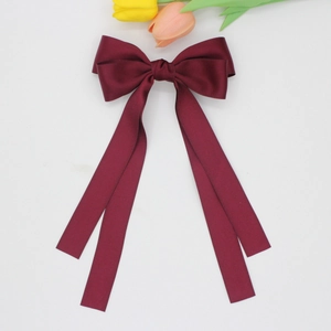 Détail d'une pince à cheveux nœud en satin bordeaux avec de longs rubans fluides