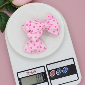 Barrette nœud rose avec cœurs sur balance, montrant un design léger de environ 10g