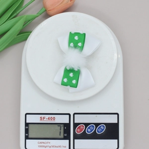 Detail view of St. Patrick's clover bow hair clip on a scale showing 7g product weight