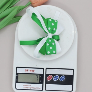 Detail shot of St. Patrick's Day clover bow clip on a digital scale showing 7g weight