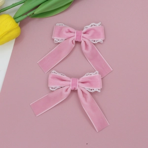 Detailansicht der rosa Samt-Haarspangen mit weißer Spitze und Tulpen-Hintergrund