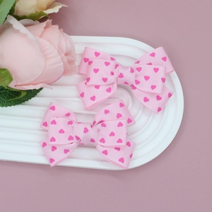 Gros plan de barrettes à cheveux en ruban gros-grain rose avec motifs de cœurs