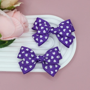 Détail de pinces à cheveux violettes à nœud en gros-grain avec motifs de cœurs blancs
