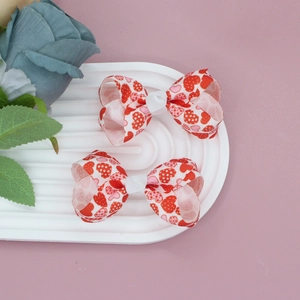 Close-up of two heart-printed ribbon bow hair clips on a white decorative display plate