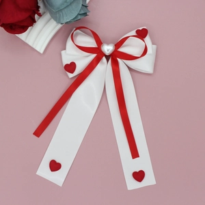 Détail d'un nœud papillon rouge et blanc avec perles cœur et longs rubans fluides