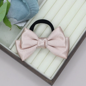 Detail of champagne pink satin double bow hair scrunchie in a white display box