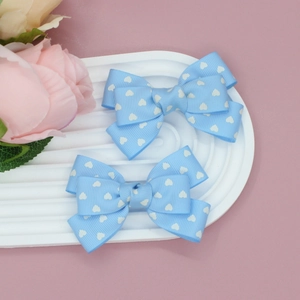 Détail de pinces à cheveux côtelées bleu clair avec motifs de cœurs blancs sur plat