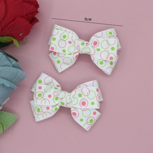 Détail de barrettes à nœuds de 9cm en ruban côtelé avec motifs rose et vert