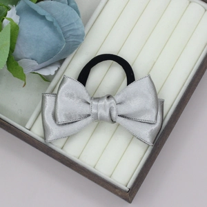 Elegant silver satin bow hair scrunchie accessory displayed in a white jewelry gift box