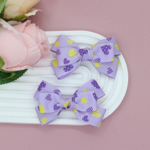 Détail de barrettes à cheveux violettes avec motifs de cœurs sur un plateau blanc ondulé