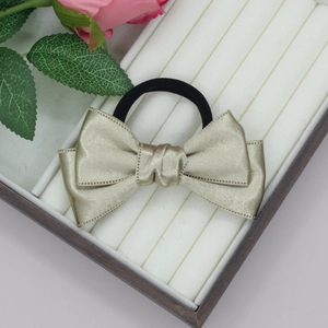 Close-up of champagne satin bow hair scrunchie with dotted edges on a white tray