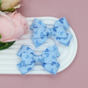 Gros plan de barrettes à cheveux en ruban gros-grain à motifs de cœurs bleus sur une assiette