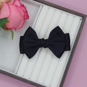 Detailansicht einer schwarzen Seidensatin-Haarschleife auf einem rosa Zubehörfach