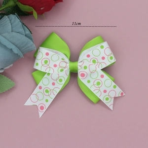 Détail d'un bandeau à nœud de 11cm en ruban gros-grain vert avec motifs à pois