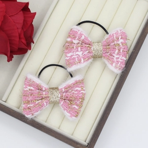 Gros plan sur chouchous nœuds en tweed rose avec paillettes dorées dans un coffret