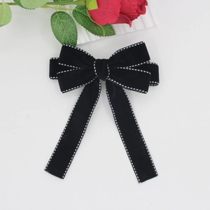 Close-up of black velvet bow hair clip with white polka dot stitching and long streamers