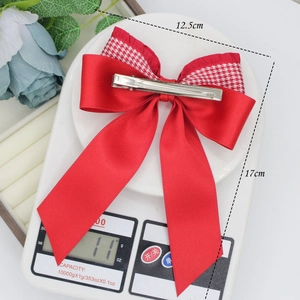 Red bow hair clip with houndstooth pattern on a scale showing 11g weight and 17cm size