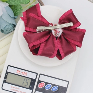 Sweet wine red bow hair clip with ruffled edges and ribbon streamer on a digital scale