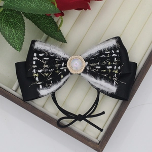 Dettaglio dell'elastico per capelli a fiocco in tweed con perla in scatola regalo