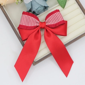 Detail of red satin bow hair clip with houndstooth pattern on a jewelry tray