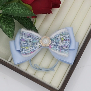 Dettaglio dell'elastico per capelli con fiocco in tweed azzurro e bottone di perla