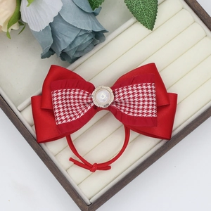 Detail of red satin and houndstooth bow hair clip with faux pearl center on white velvet