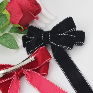 Detail of red and black velvet bow hair clips with white dotted stitching and metal clips