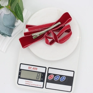 Detail view of a red velvet bow hair clip with white dots on a scale weighing 8g