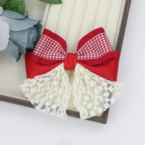Close-up of red houndstooth bow hair clip with white lace embroidery detail