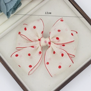 Detailed view of a 12cm cream hair bow with red polka dots and fine edge stitching