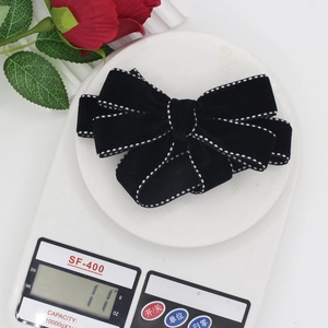 Detailed weight measurement of black velvet bow hair clip showing 11g on electronic scale