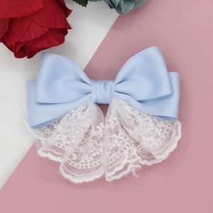 Fermaglio per capelli fiocco in raso azzurro con pizzo bianco su sfondo rosa e bianco