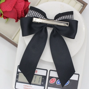 Houndstooth black bow hair clip with streamer tail shown on a scale weighing 11g