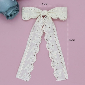 Detailed view of cream lace hair bow with long streamers measuring 13cm by 21cm