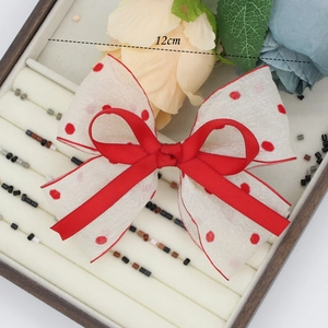 Detail showing red polka dot chiffon bow hair clip with 12cm width measurement