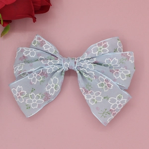 Détail de la pince à cheveux en mousseline bleue avec fleurs de cerisier sur fond rose