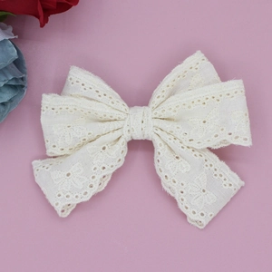 Detailed macro view of cream lace bow hair clip with intricate embroidery pattern