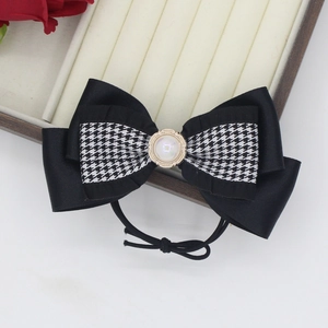 Detail of elegant houndstooth bow hair clip with white pearl accent on satin finish