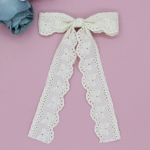 Close-up of cream lace bow hair clip with elegant long ribbons and wavy edges